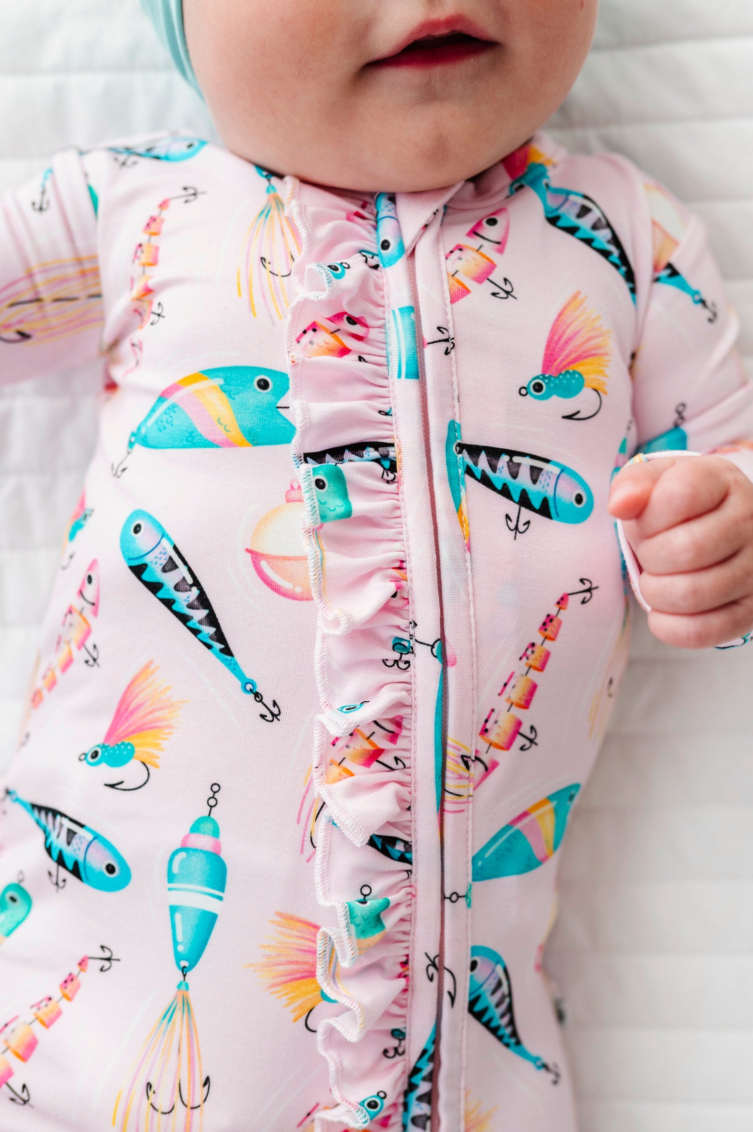 Baby wearing a colorful bamboo zip romper with fishing-themed design on a white background