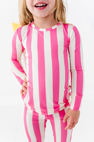 A young girl wearing a pink and white vertically striped long-sleeve top and matching striped pants, shown from the mouth down against a clean white background.