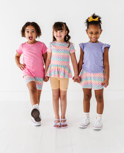 Three children wearing colorful bamboo outfits standing together on a white background