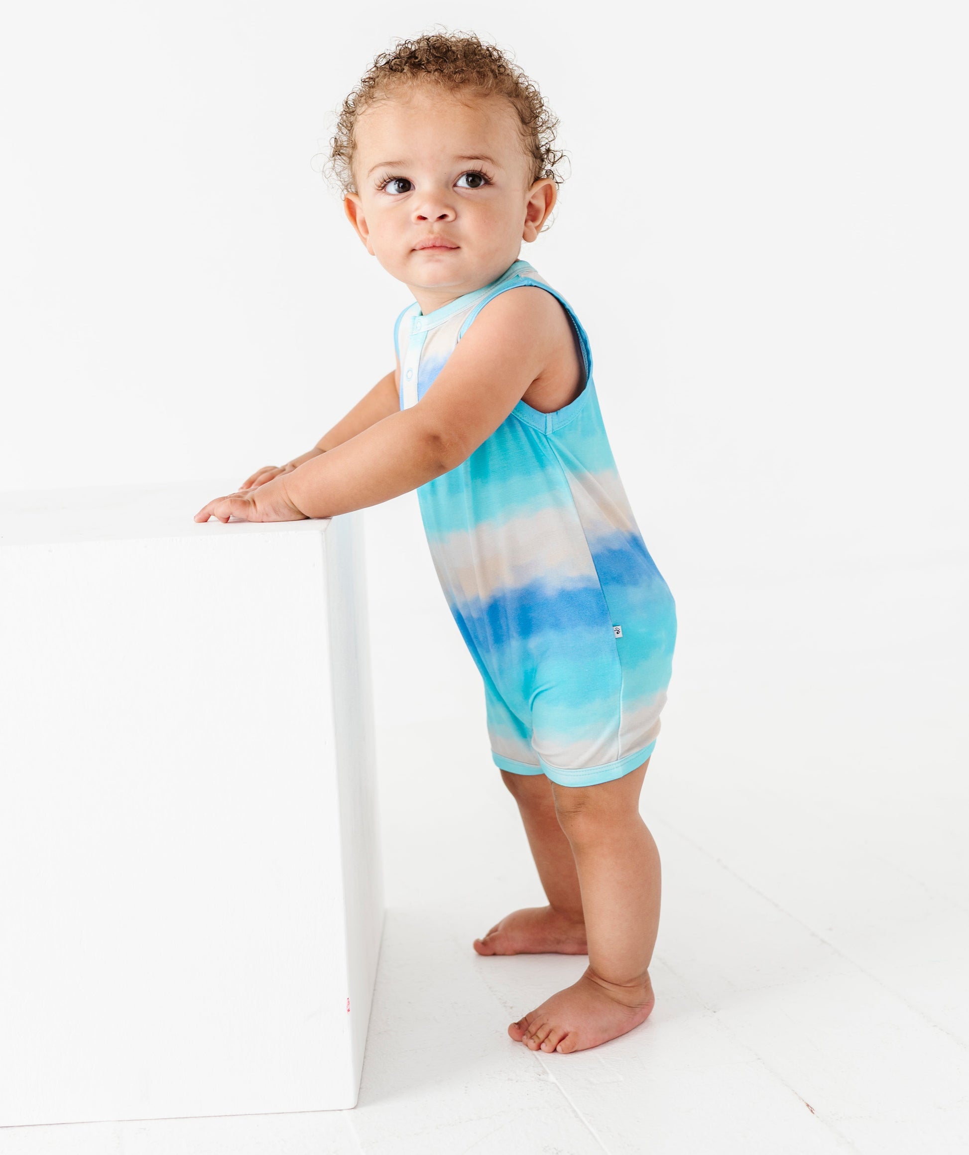 Child wearing a tie-dye bamboo romper on a white background