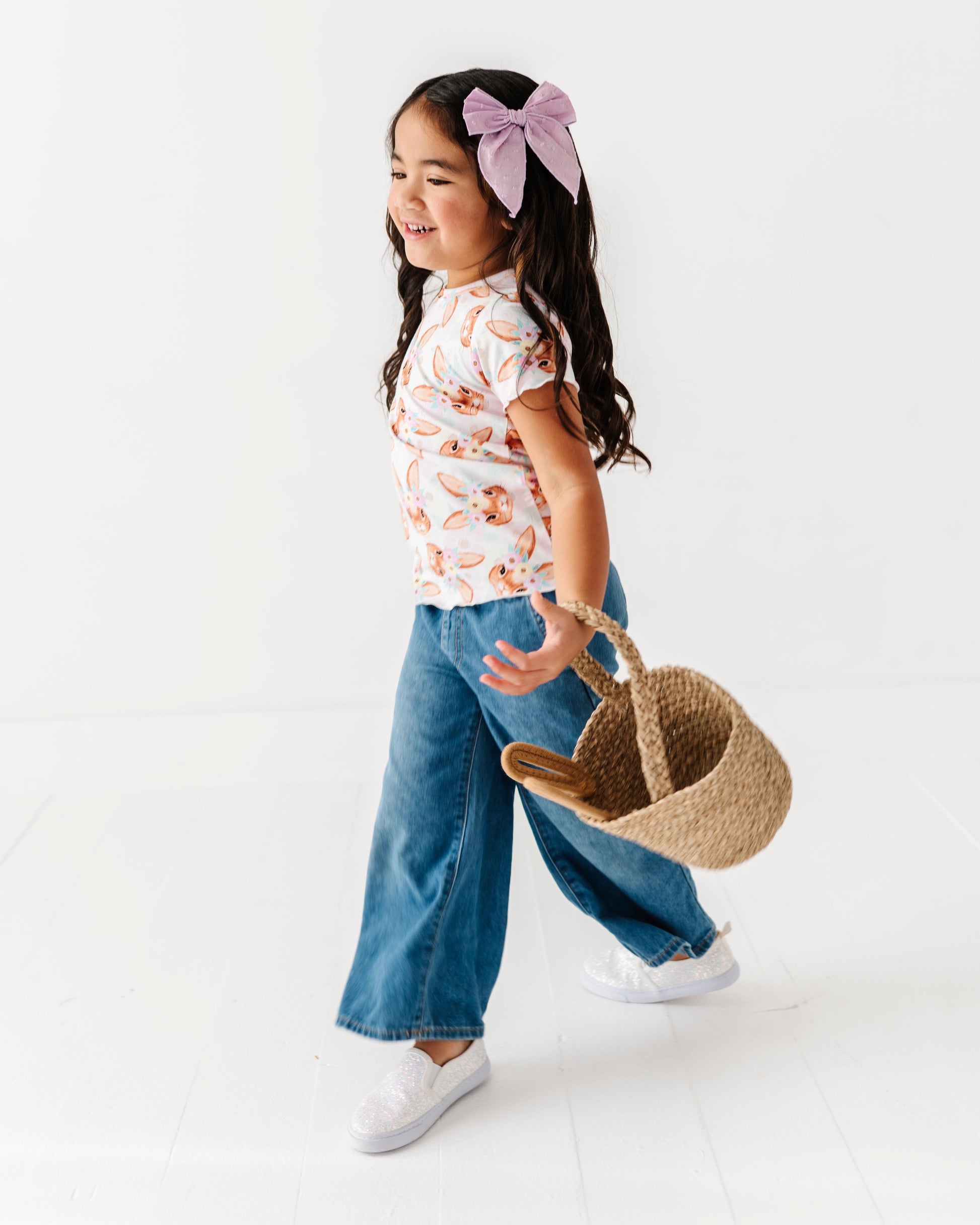 Young girl holding a woven bag with a white background