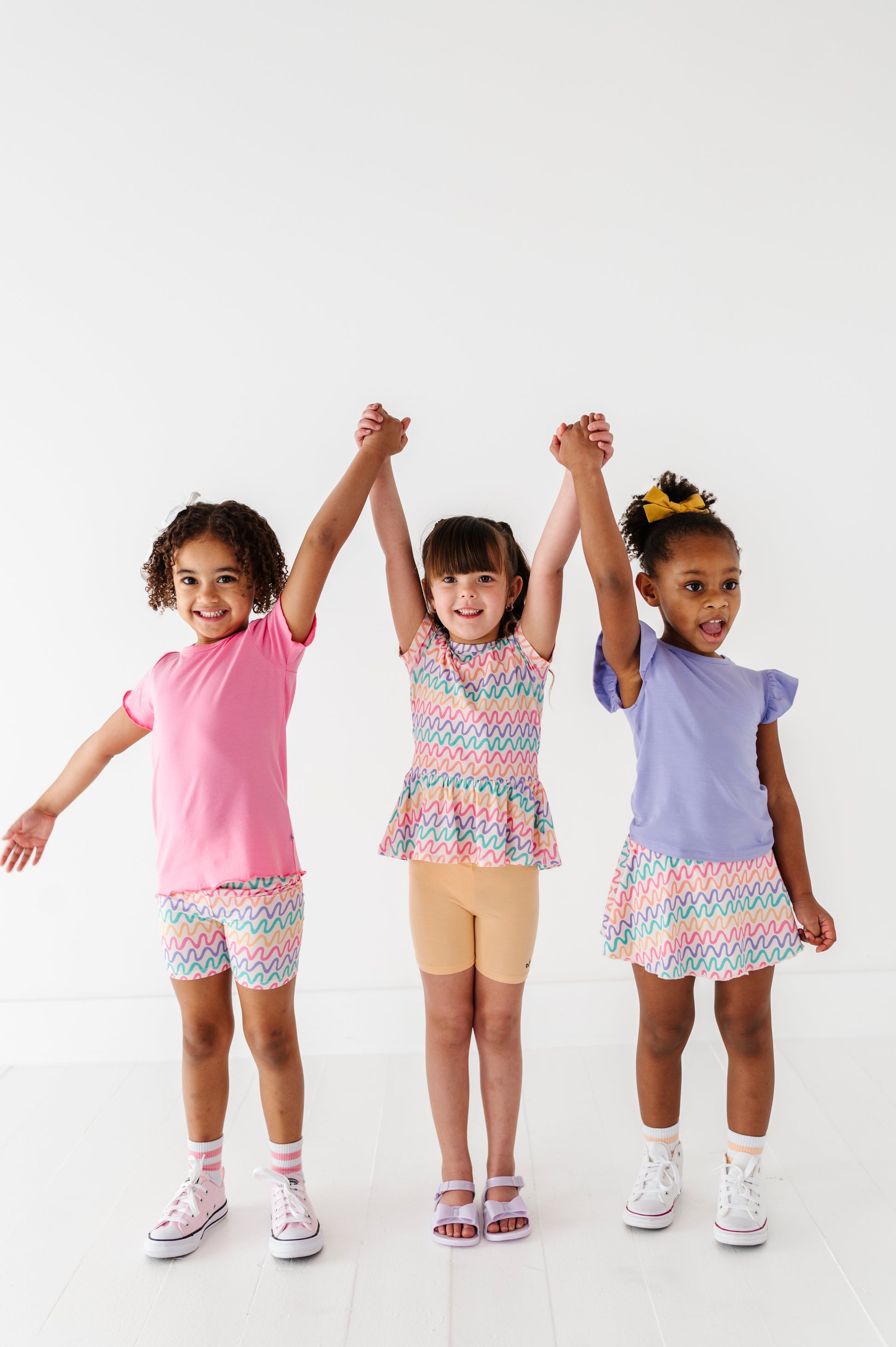 Three children wearing colorful bamboo outfits standing together on a white background