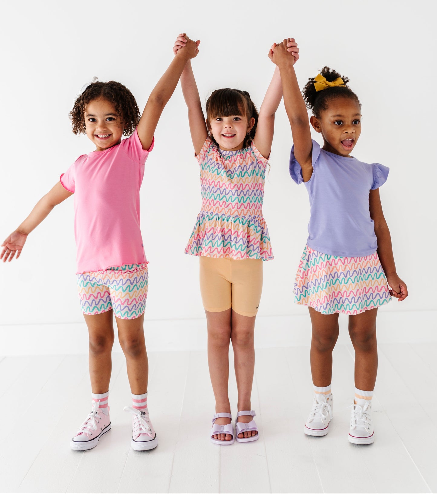 Three children wearing colorful bamboo outfits standing together on a white background