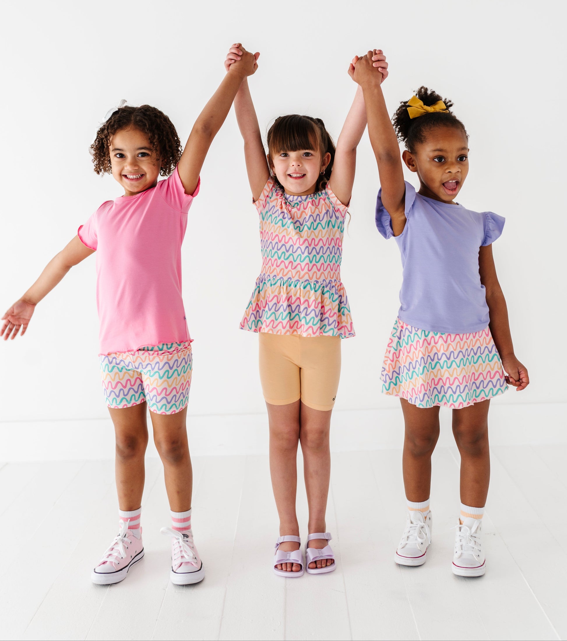 Three children wearing colorful bamboo outfits standing together on a white background