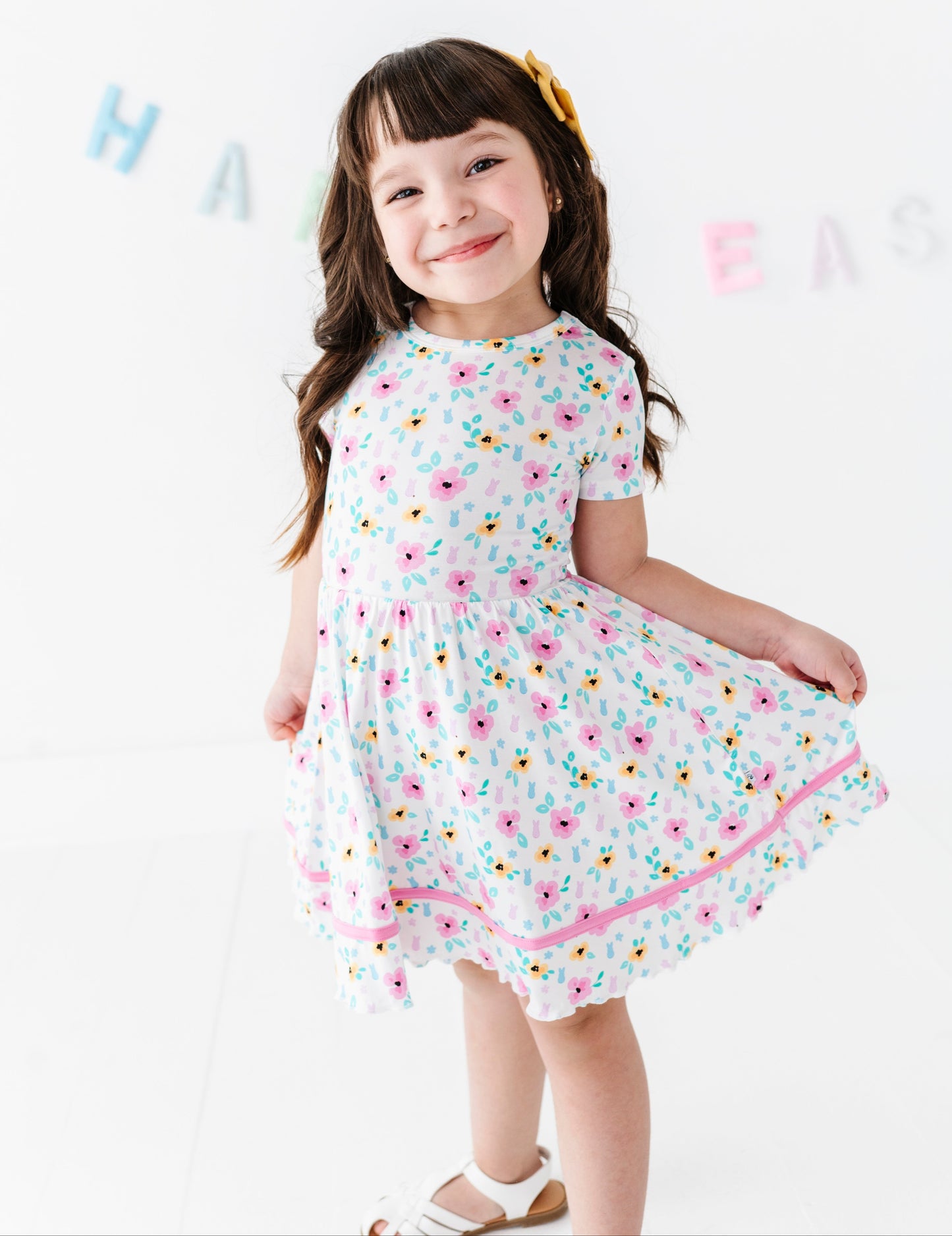 Young girl in a floral PEEPS® dress standing against a white background with 'Happy Easer' banner.
