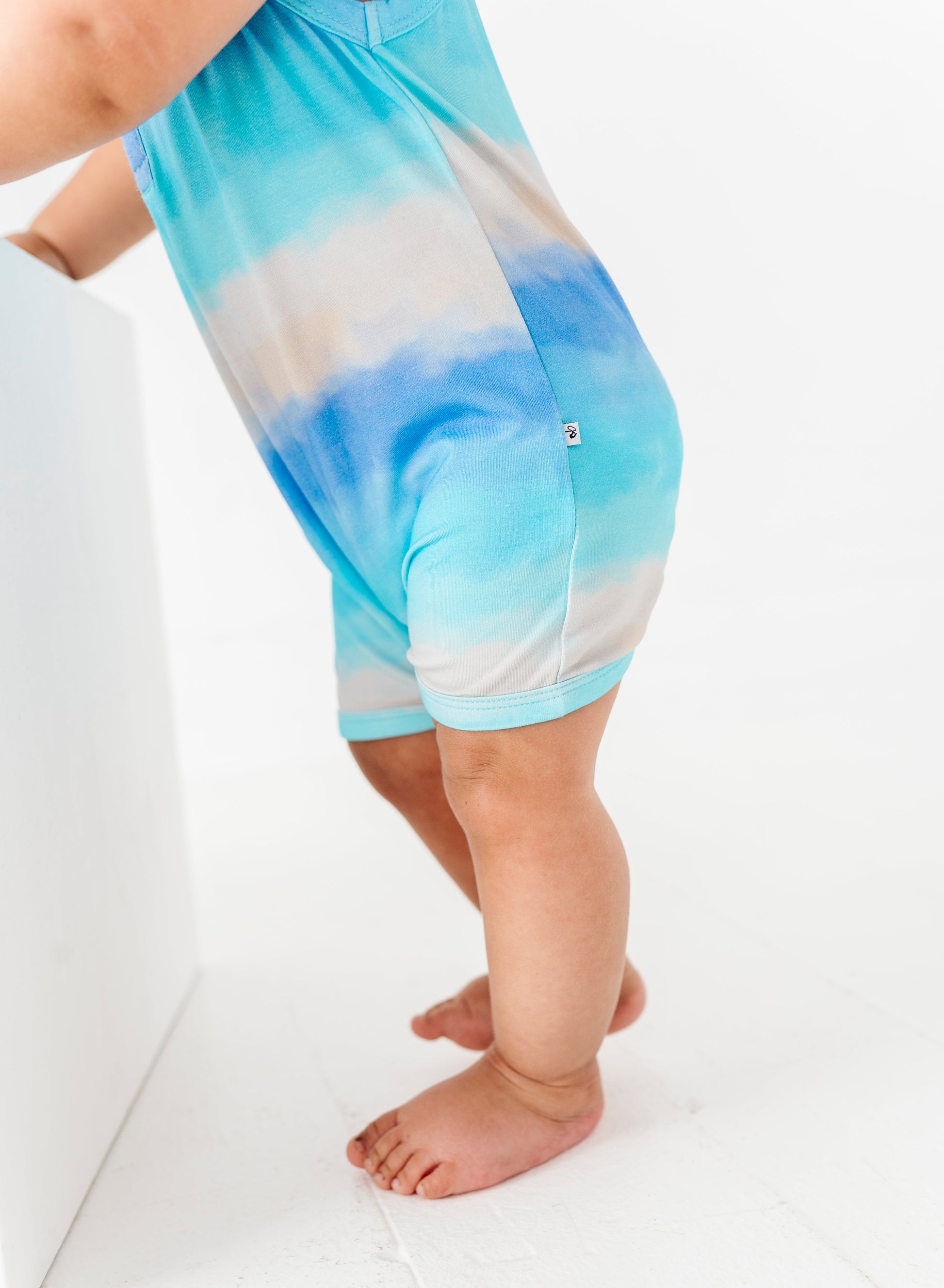 Baby wearing tie-dye bamboo romper on a white background