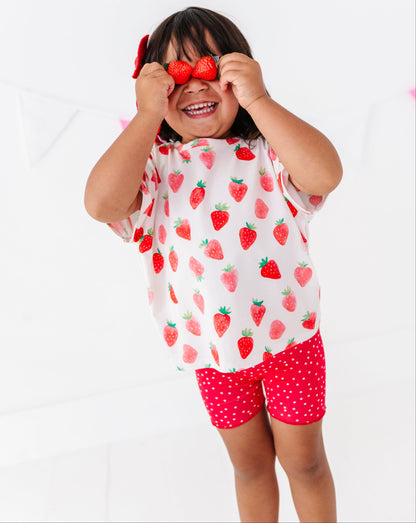 Child wearing a strawberry-patterned outfit on a white background