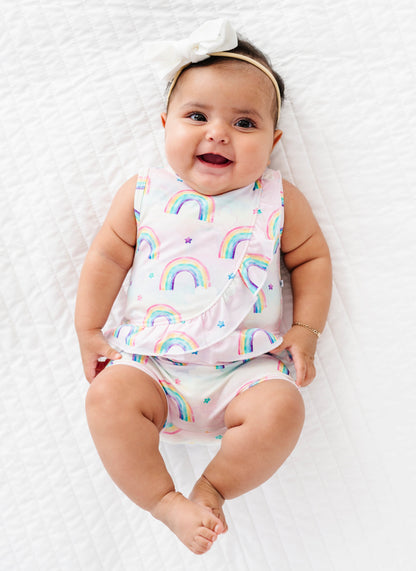 Baby wearing a watercolor rainbow-patterned bamboo cotton outfit on a white background