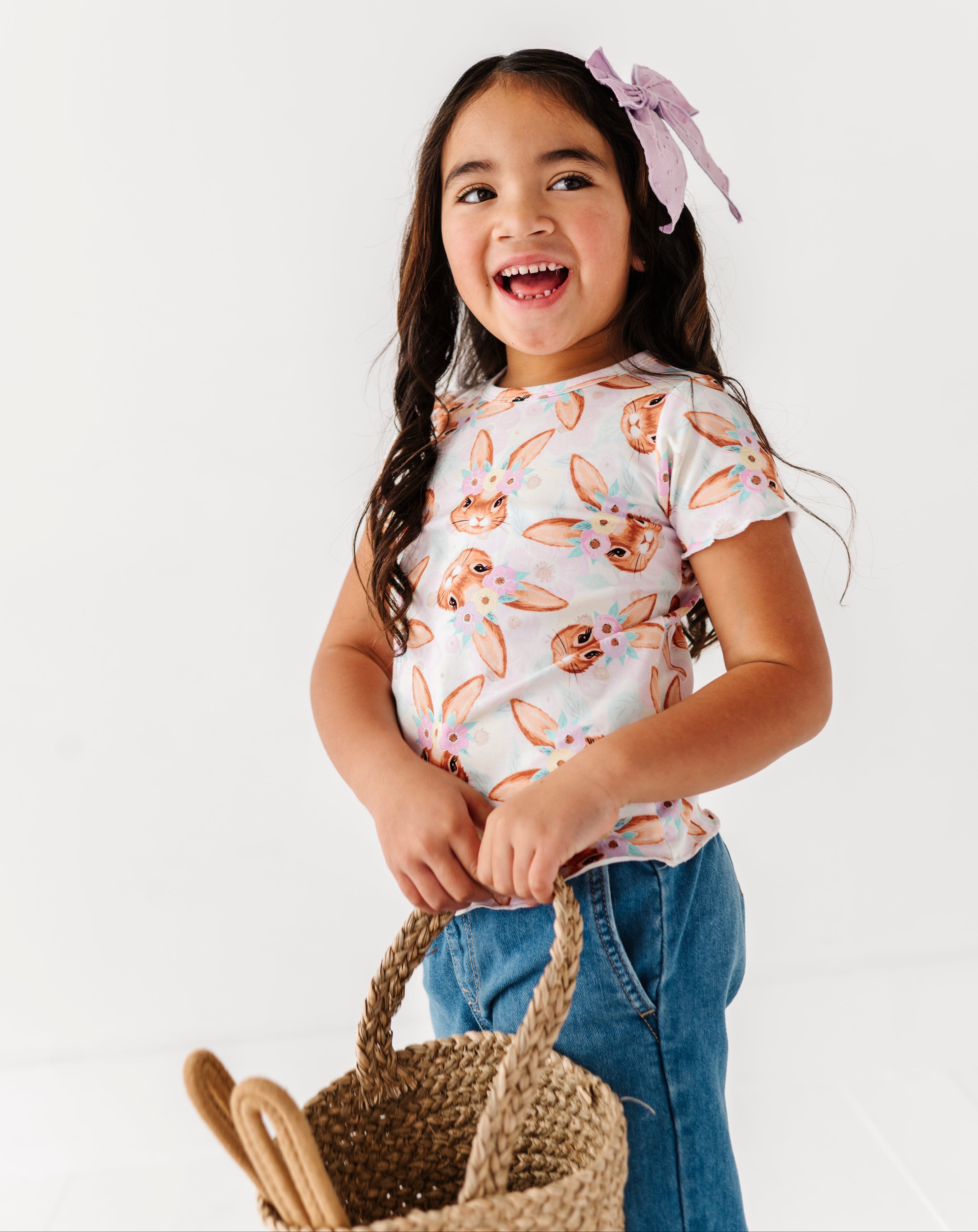 Young girl wearing a patterned shirt and holding a basket on a white background