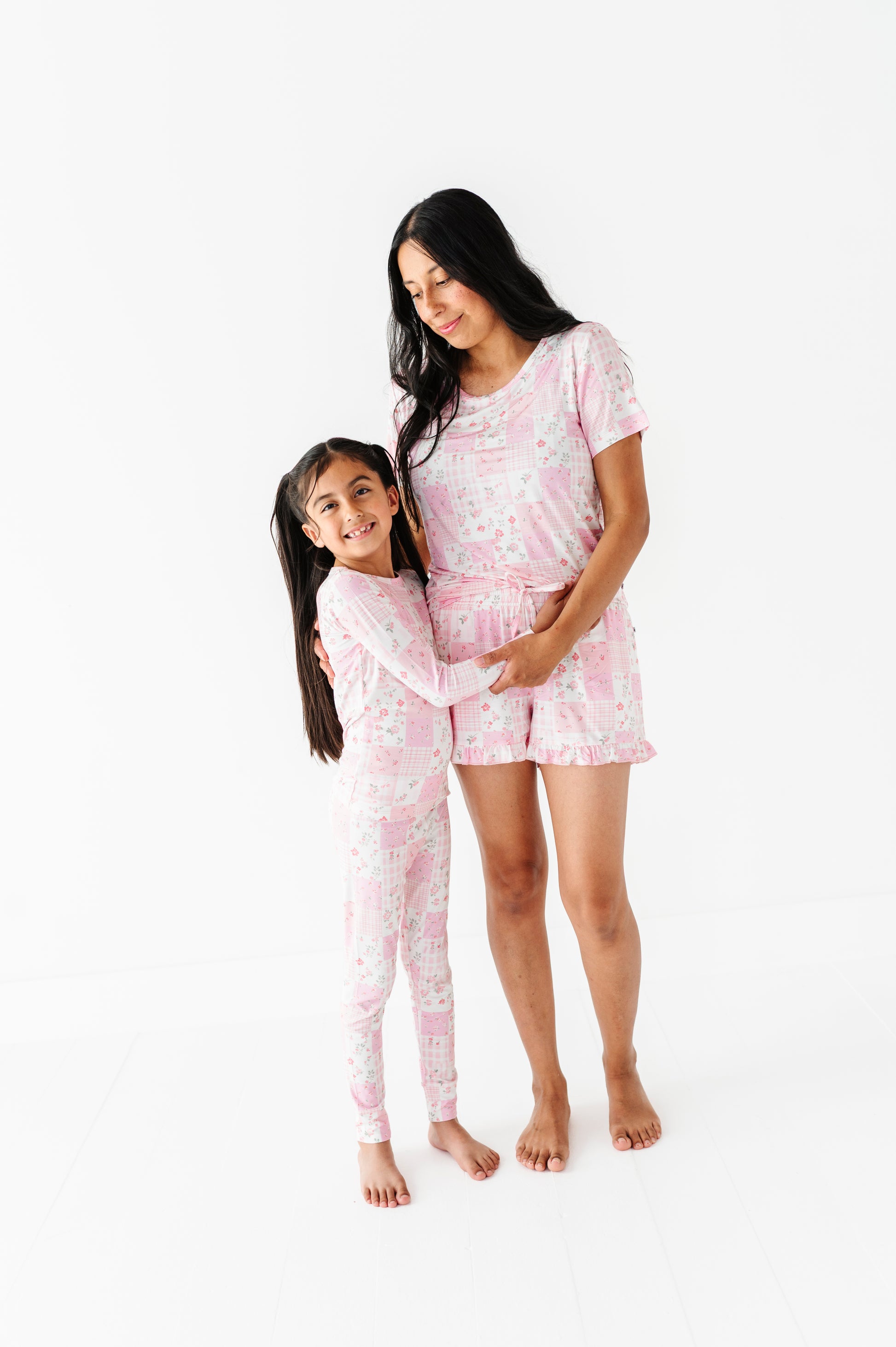 Woman and child wearing matching pink bamboo pajama sets on a white background