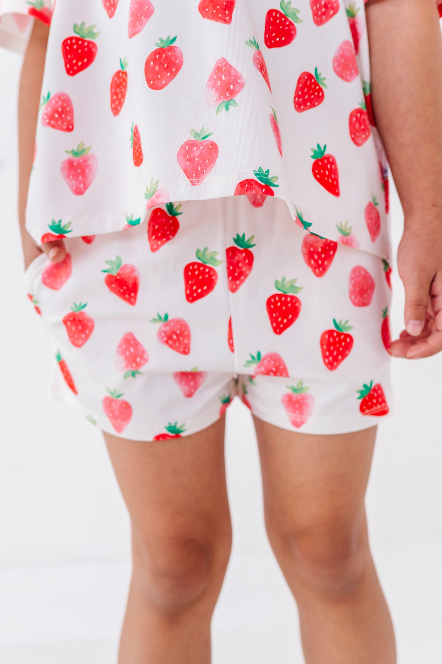 White outfit with red strawberry pattern worn by a person on a white background