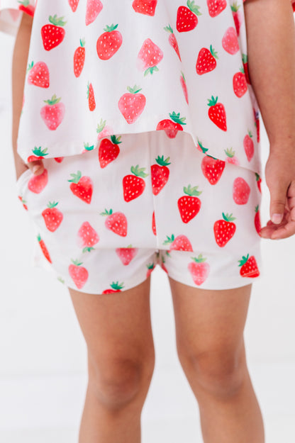 White outfit with red strawberry pattern worn by a person on a white background