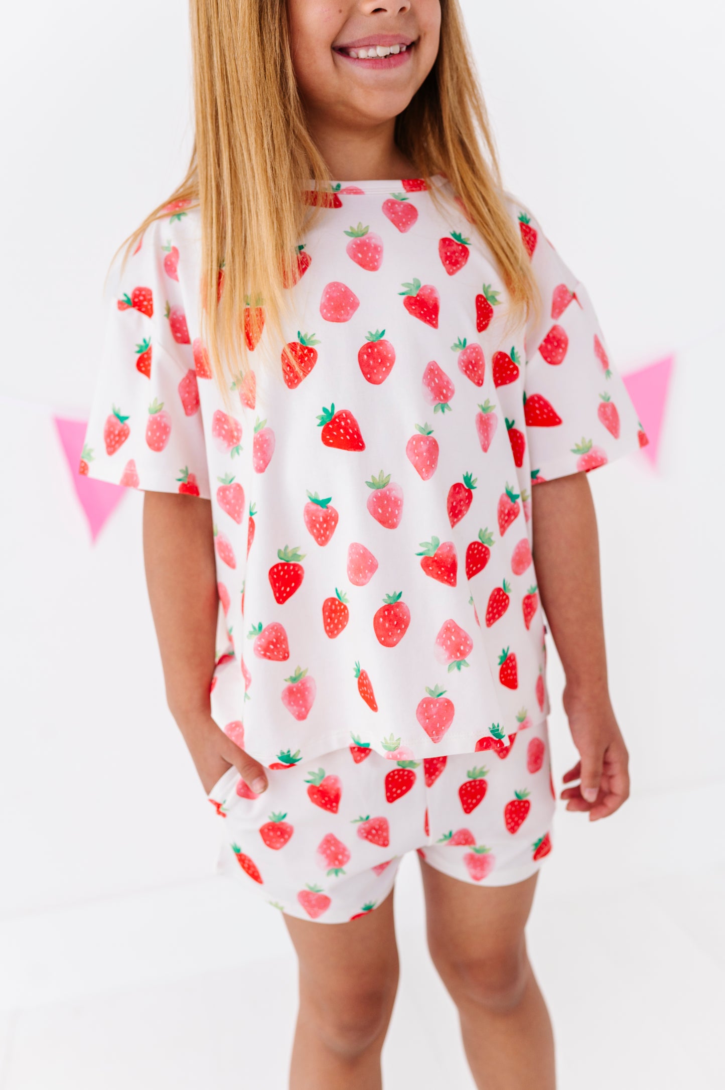 Child wearing a strawberry-patterned outfit on a white background