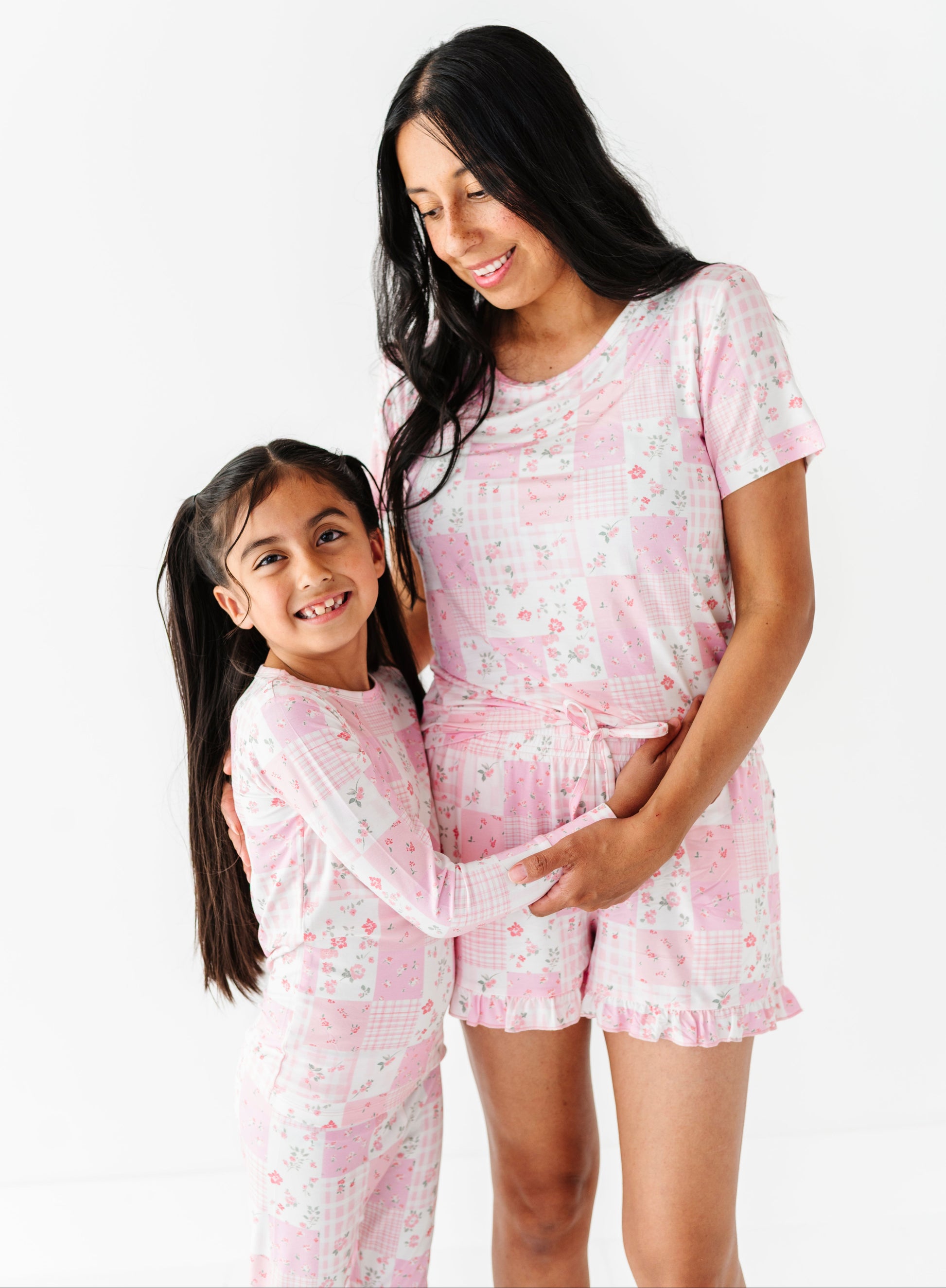 Mama and mini wearing pink bamboo two-piece pajamas with a floral pattern on a white background