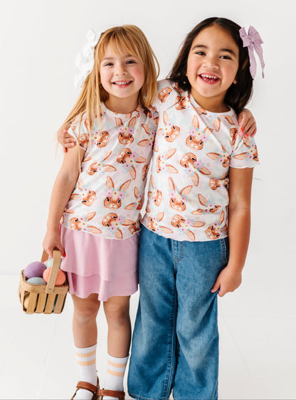 Two children wearing matching floral tops and colorful bottoms on a white background