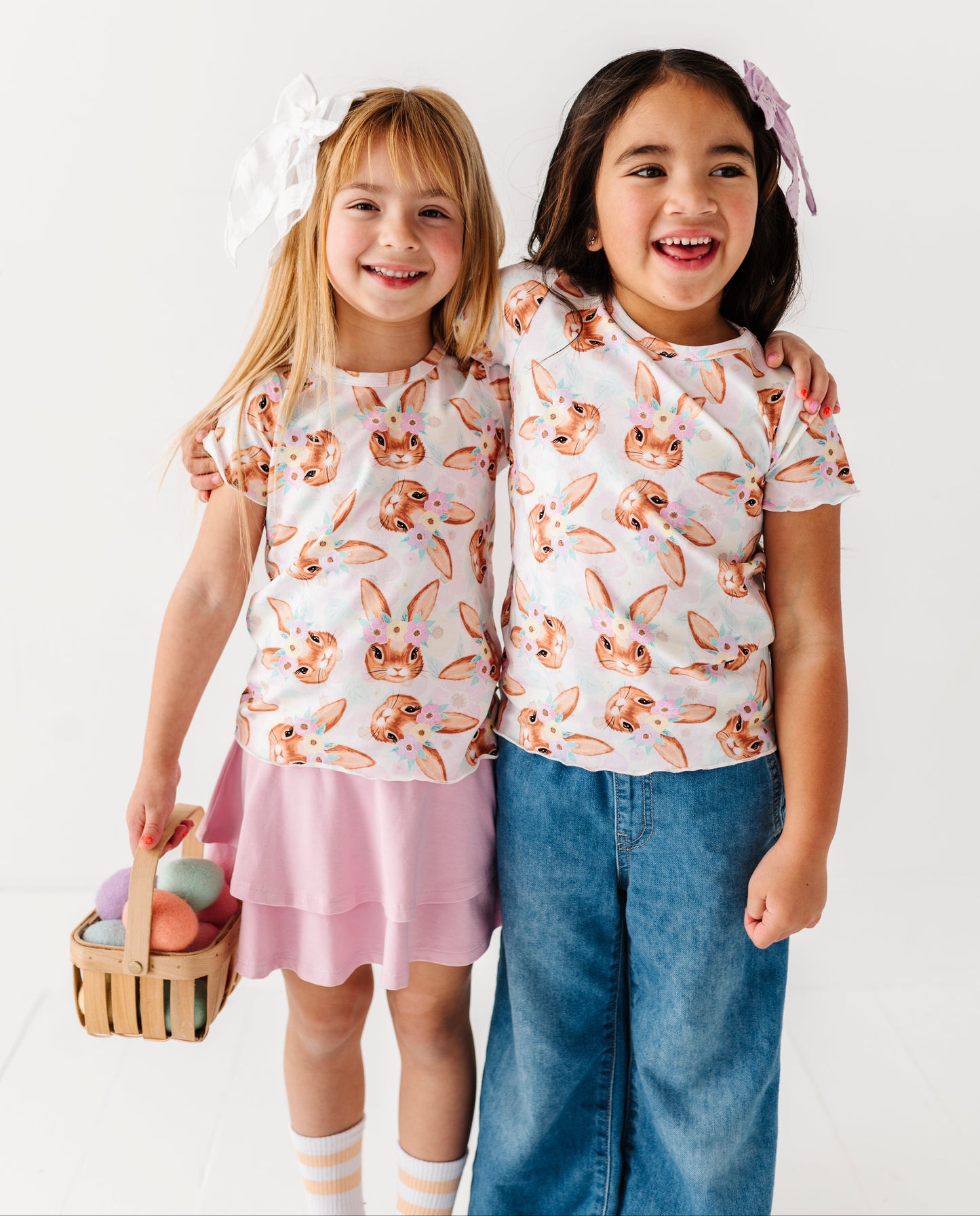 Two children wearing matching outfits with bunny print on a white background