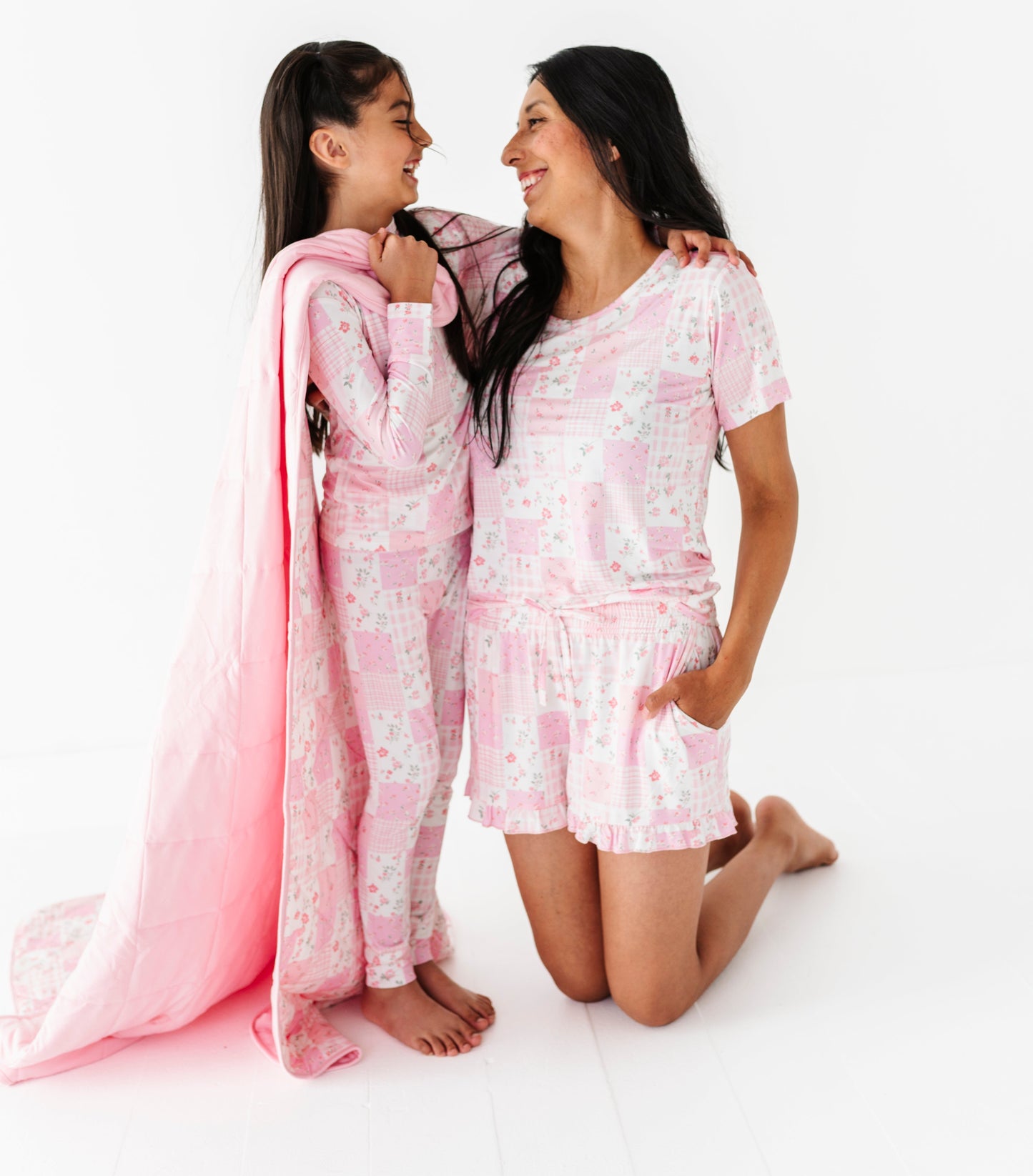 Mother and daughter in matching pajama sets on a white background