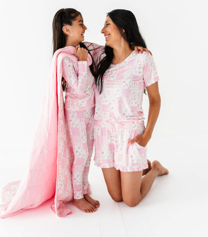 Mother and daughter in matching pajama sets on a white background
