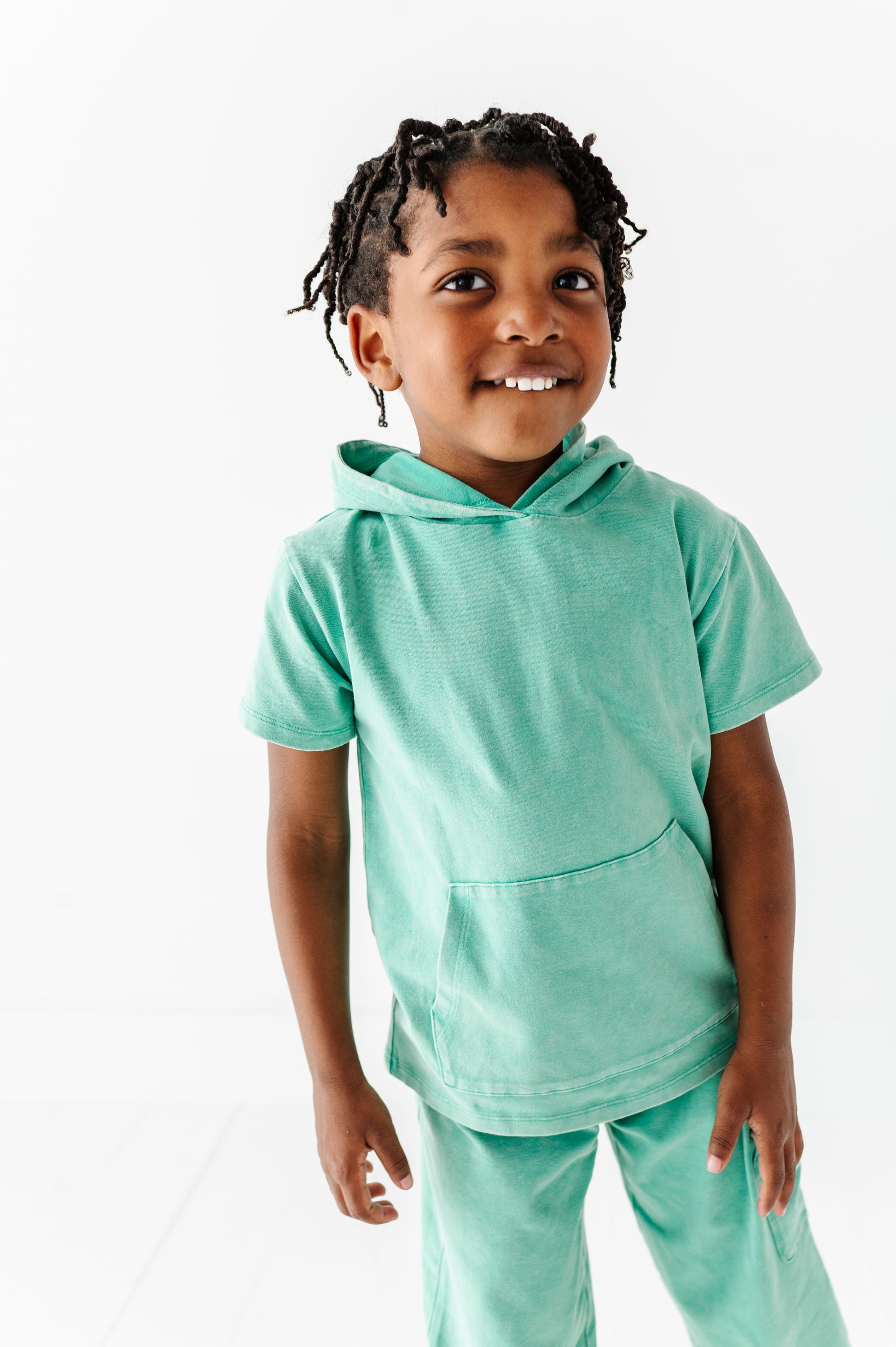 Child wearing a light green hoodie and pants on a white background
