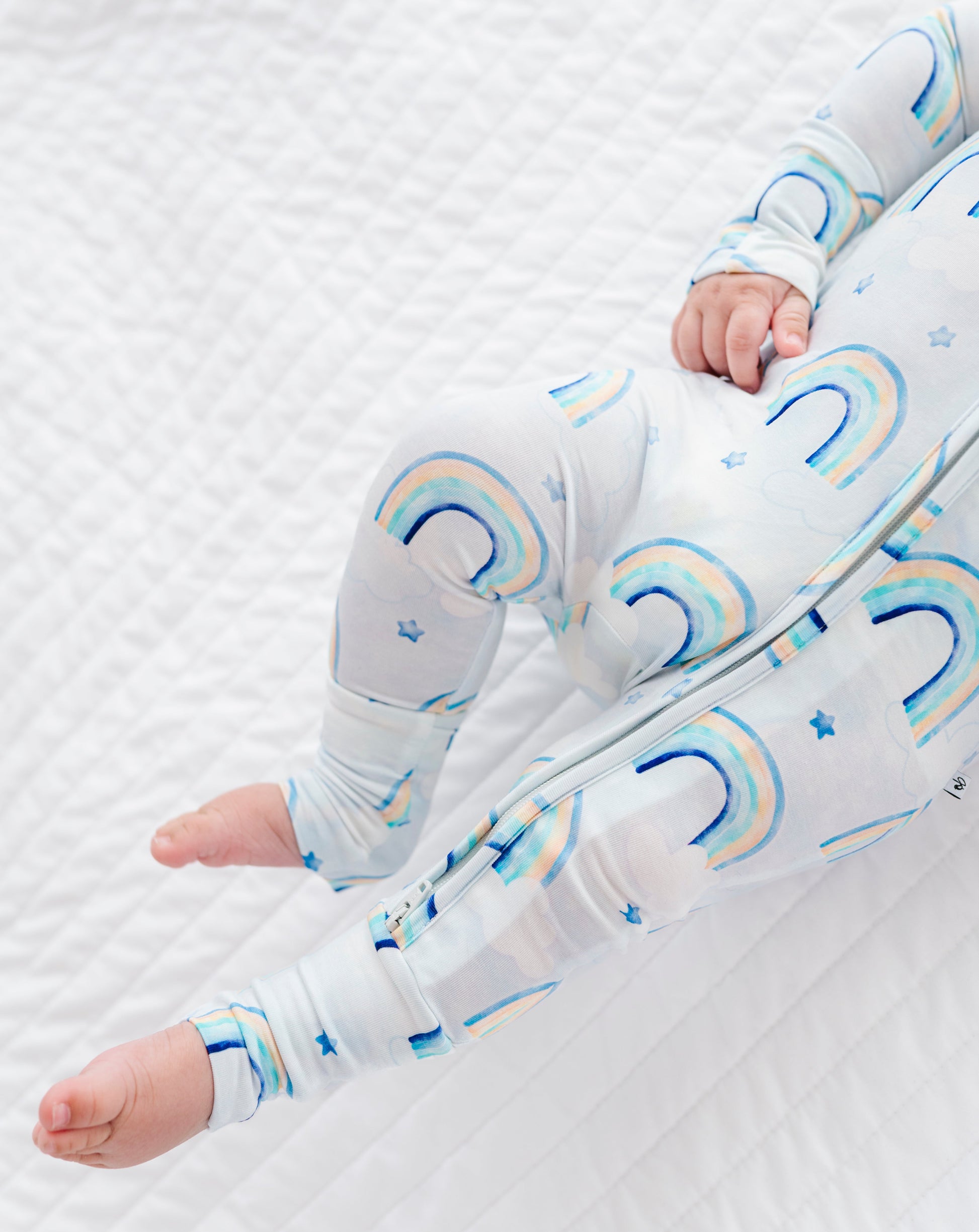 Baby in a crib with rainbow-patterned bamboo zip romper