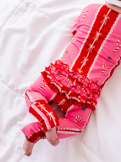 A close-up shot of the back ruffles on a baby girl wearing a red-and-pink bamboo Christmas convertible romper featuring ruffle detailing and foldover cuffs 