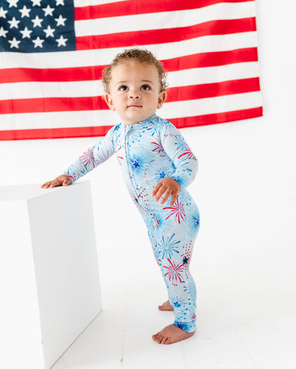Child wearing a patriotic bamboo zip romper with a USA flag in the background