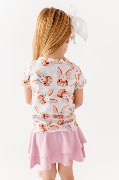 Child wearing a white shirt with bunny print and pink skirt on a white background