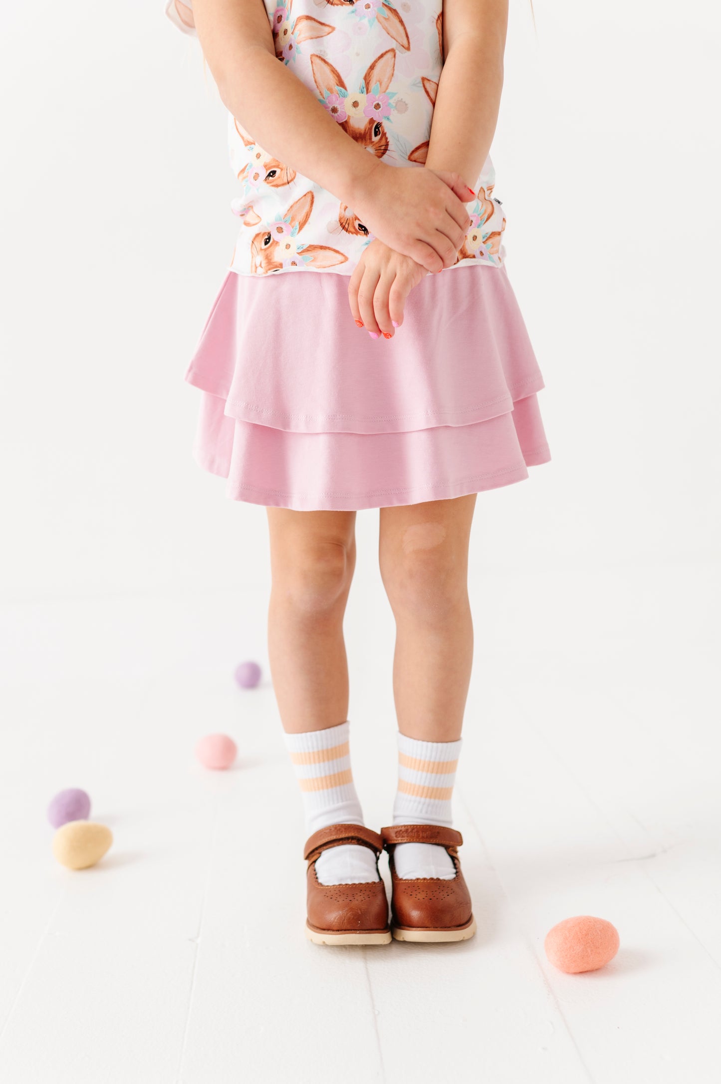 Child wearing a pink skirt with a white background