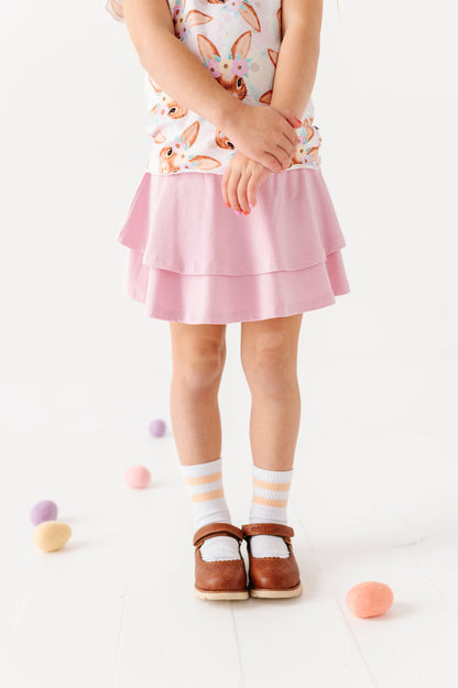 Child wearing a pink skirt with a white background
