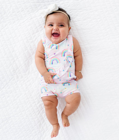 Baby wearing a rainbow-patterned bamboo cotton outfit lying on a white surface