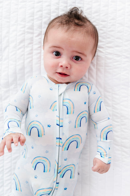 Baby wearing a bamboo convertible romper with watercolor rainbow patterns on a white background