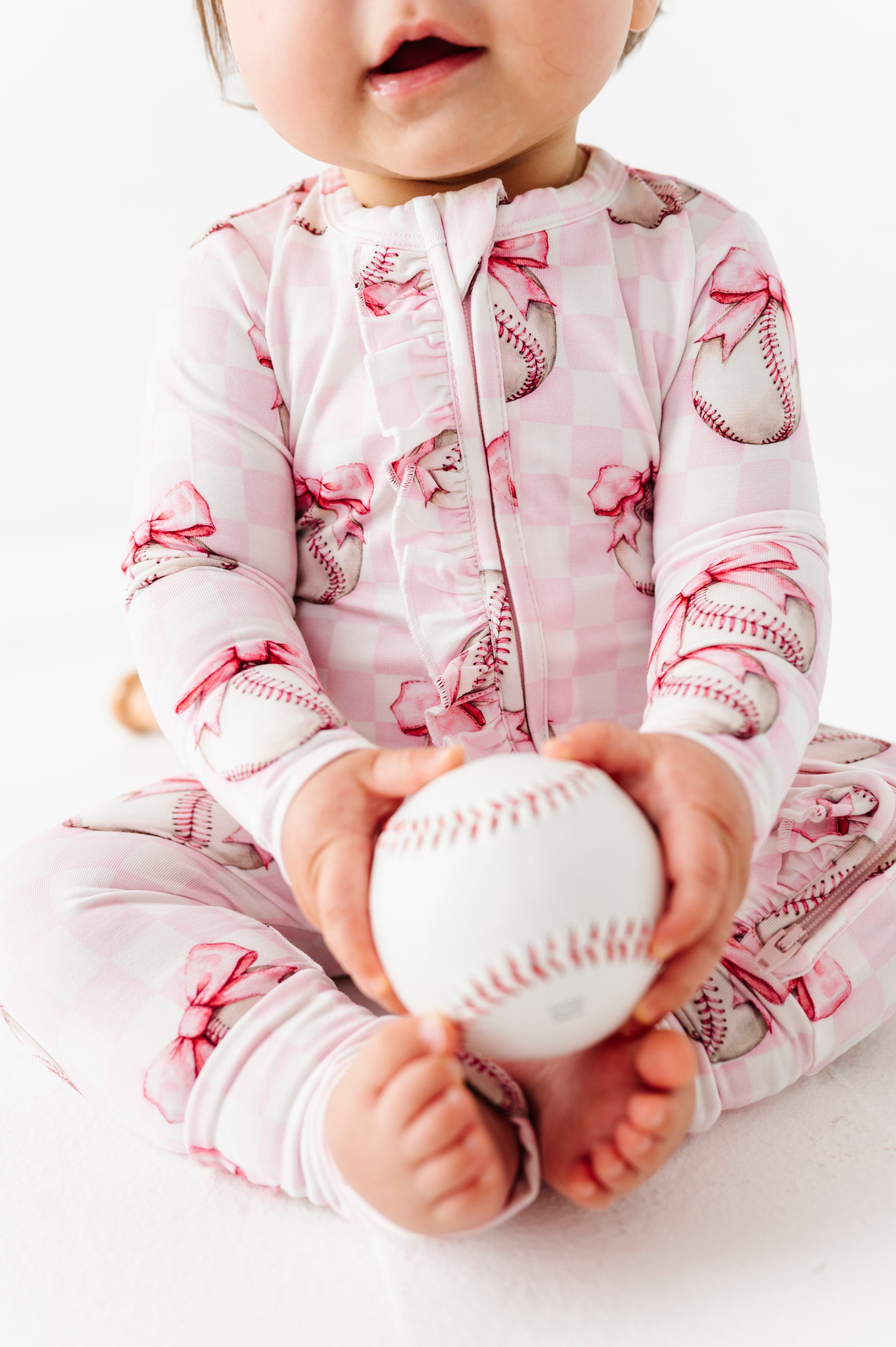 Baby holding a baseball wearing bamboo pajamas