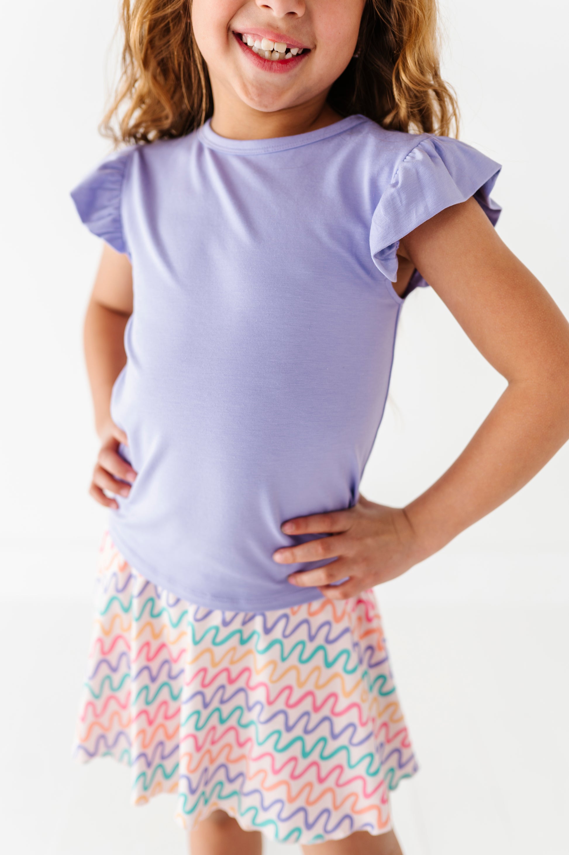 Young girl wearing a purple top and colorful skirt on a white background