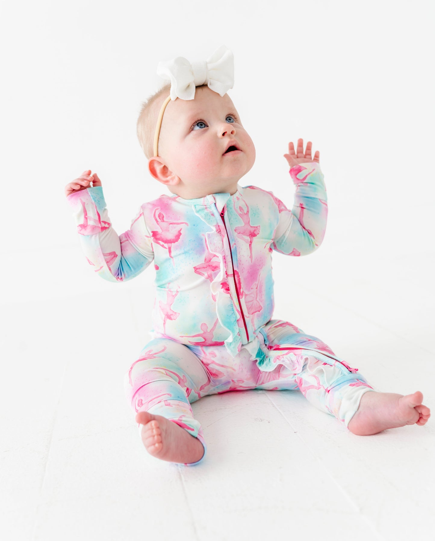 Baby wearing a colorful bamboo onesie with watercolor ballerina design on a white background