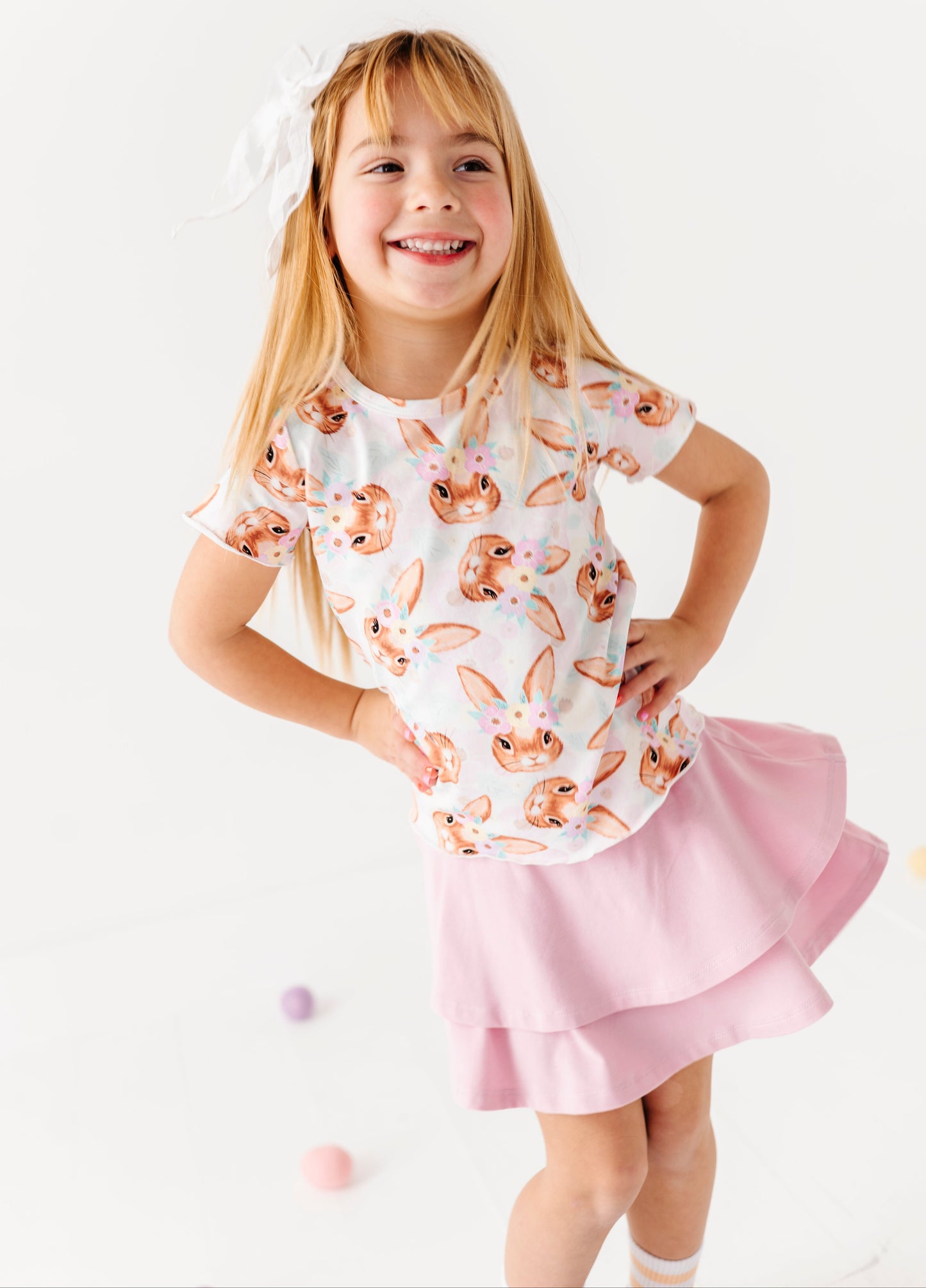 Child wearing a bamboo shirt with bunny print and pink skirt on a white background