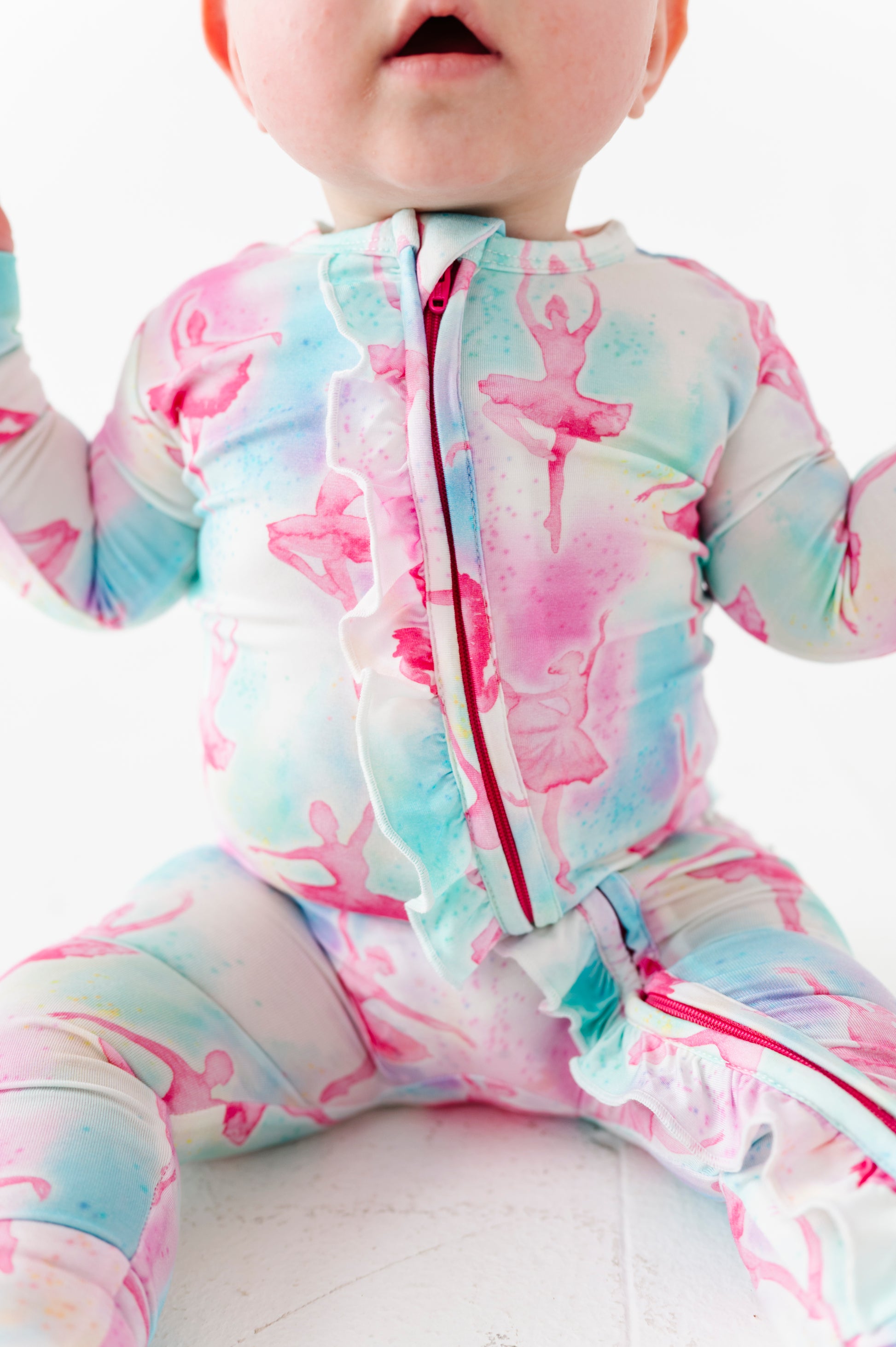 Baby in a watercolor bamboo convertible romper against a white background 