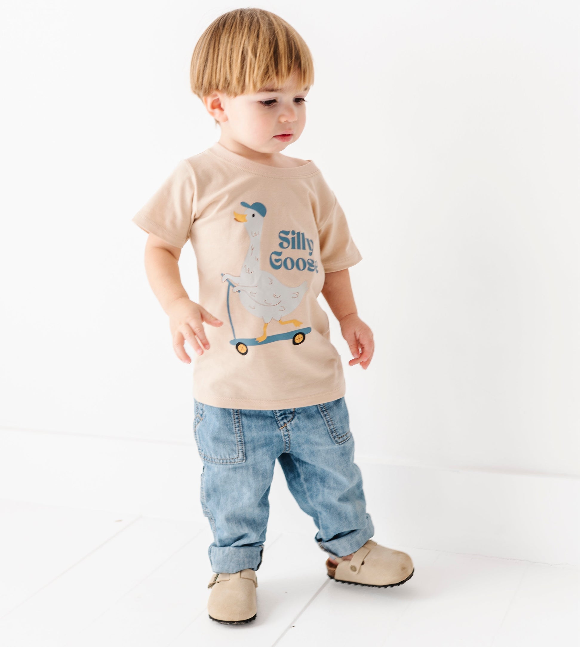 toddler boy wearing a "silly goose" t-shirt with jeans on a white background 