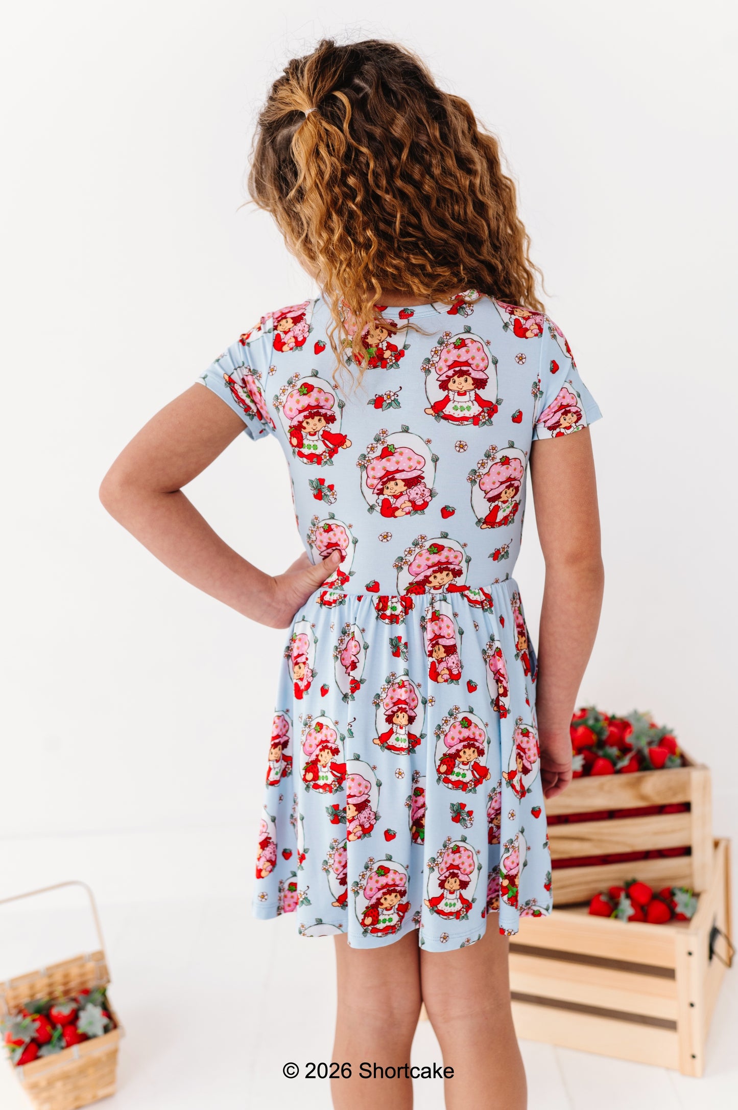 Girl wearing a Strawberry Shortcake™ dress with a white background