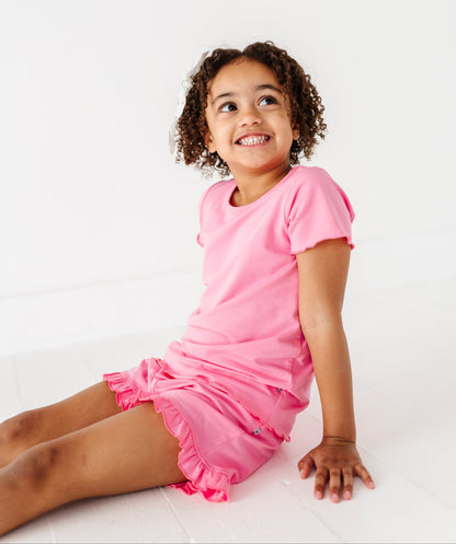 Young girl wearing a pink bamboo/cotton outfit sitting on a white background