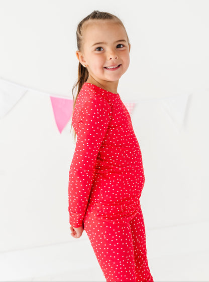 Young girl wearing  red polka dot pajamas on a white background