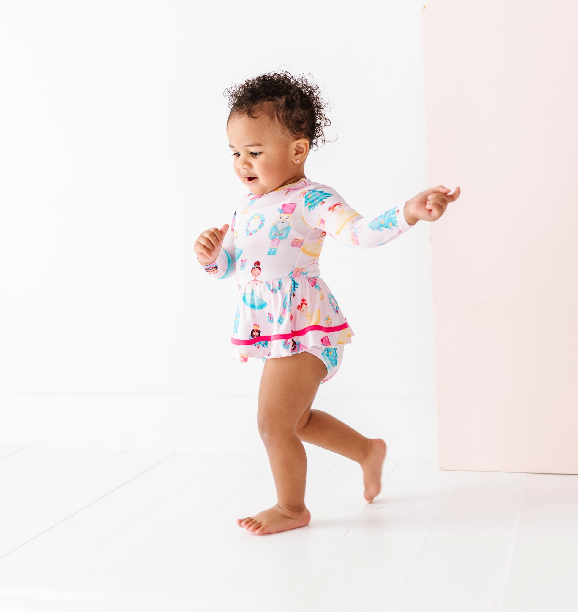 Child wearing a light pink Christmas bamboo dress with a bodysuit underneath 