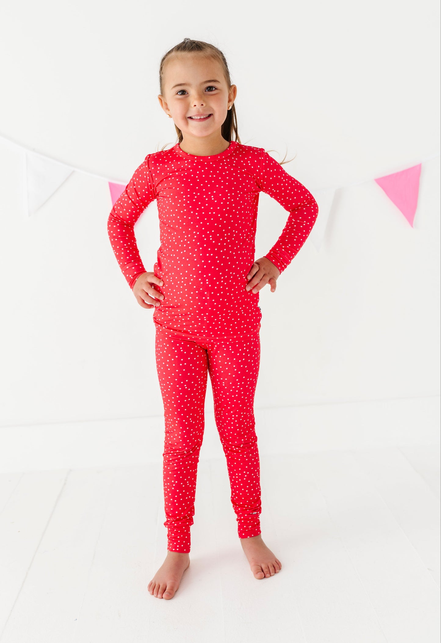 Young girl wearing a red pajama set with white dots on a white background