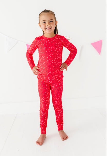 Young girl wearing a red pajama set with white dots on a white background