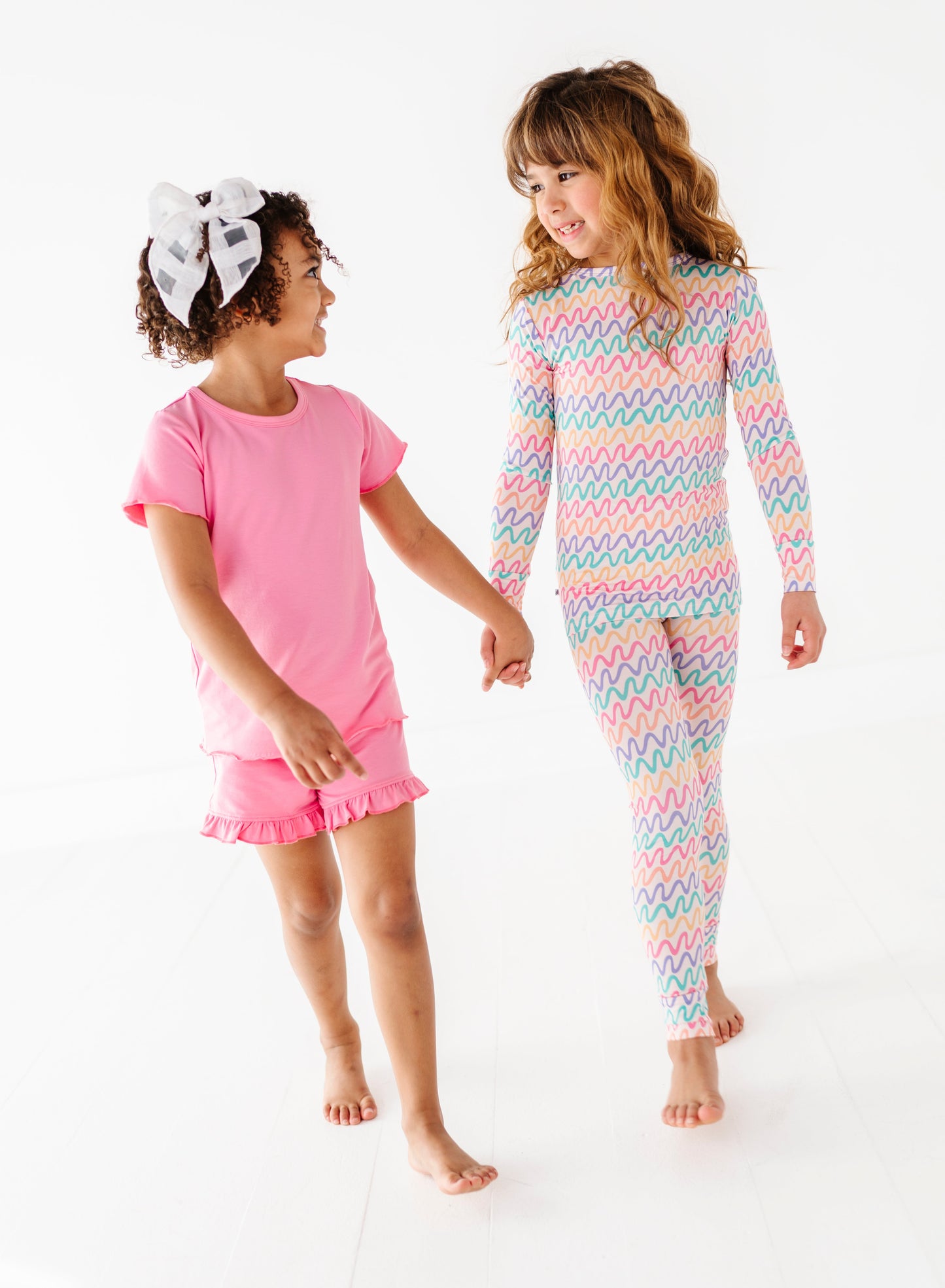 Two children wearing colorful bamboo pajamas on a white background