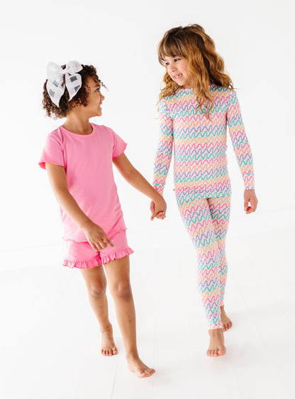 Two little girls walking together, one wearing bamboo pajamas and a pink bamboo/cotton top and shorts 