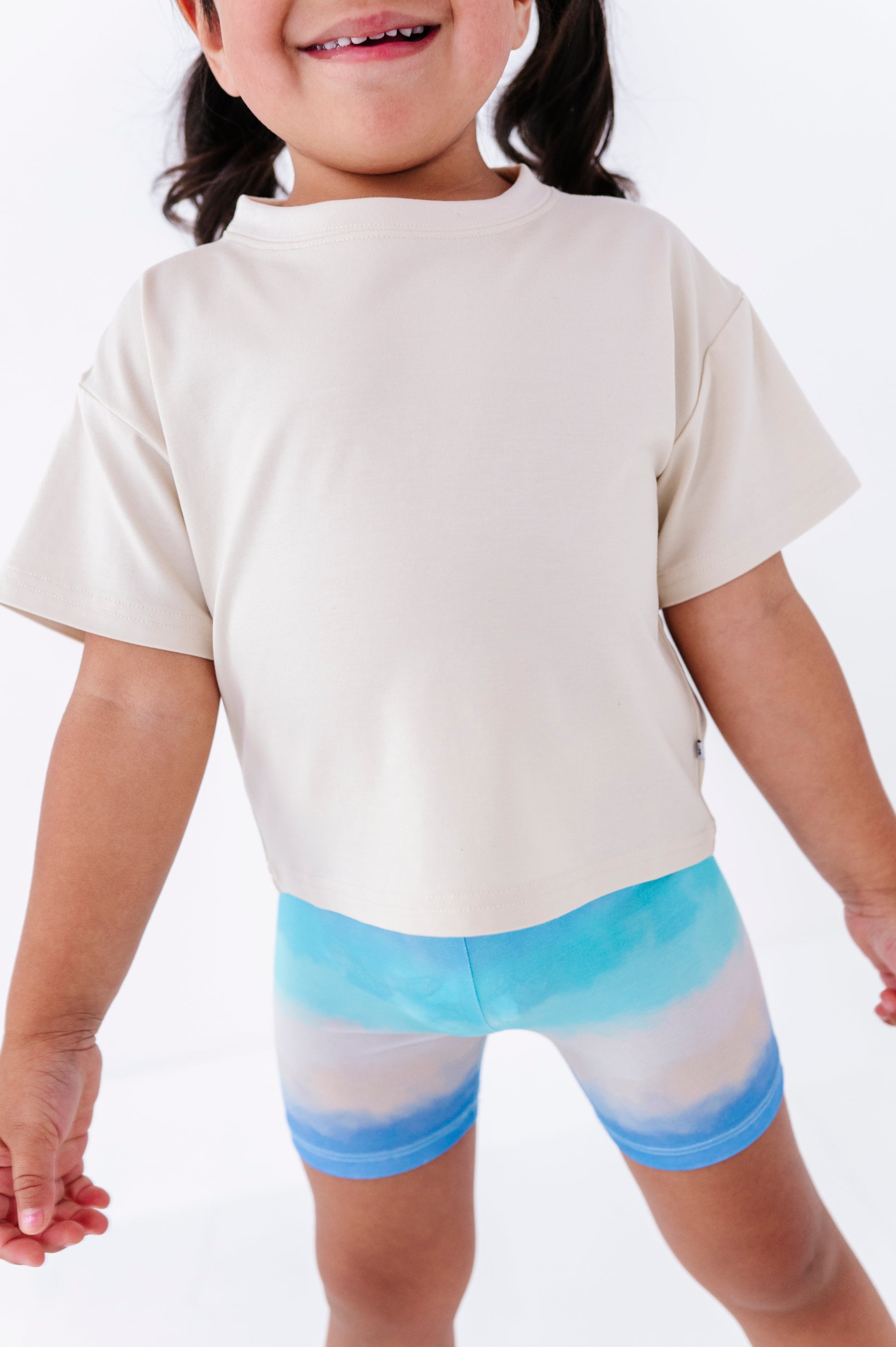 Child wearing an ivory shirt and bamboo biker shorts on a plain background
