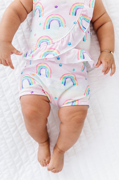 Baby wearing a bamboo cotton outfit with watercolor rainbow patterns on a white background