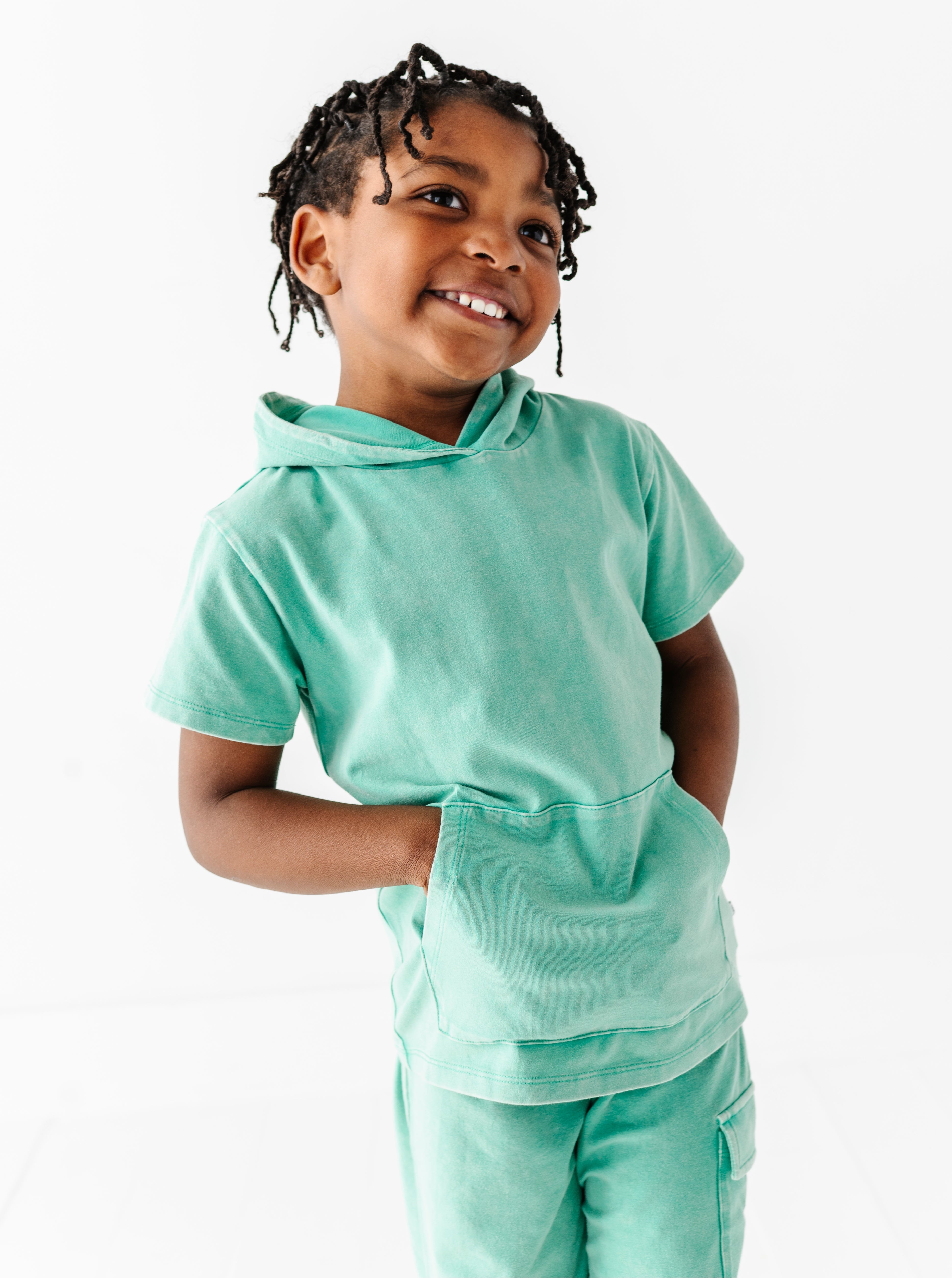 Child wearing a light green hoodie and pants on a white background