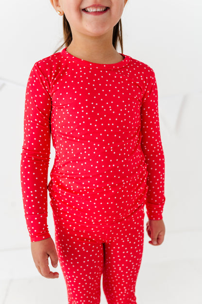 Child wearing red pajamas with white polka dots on a white background
