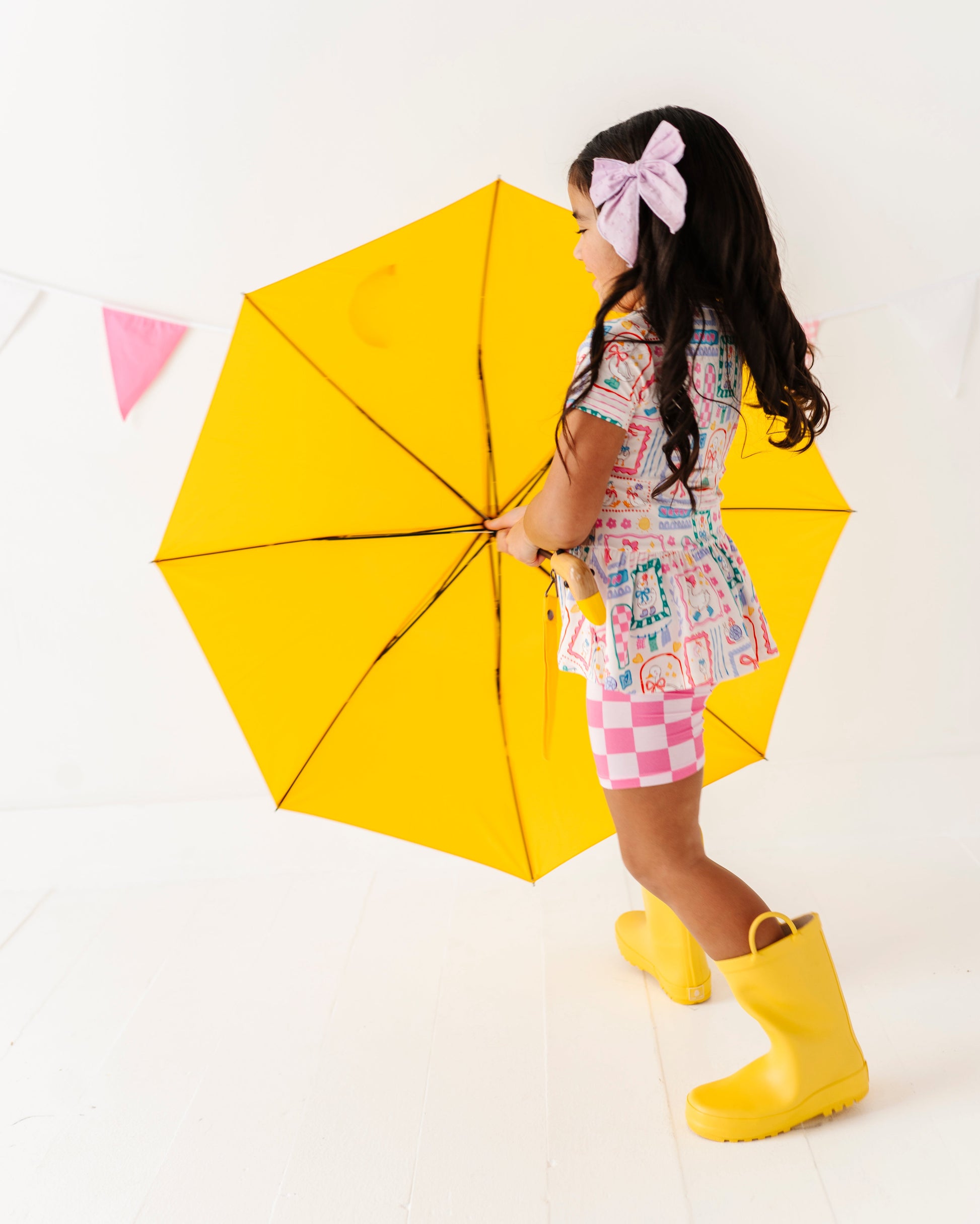 Child holding a yellow umbrella on a white background